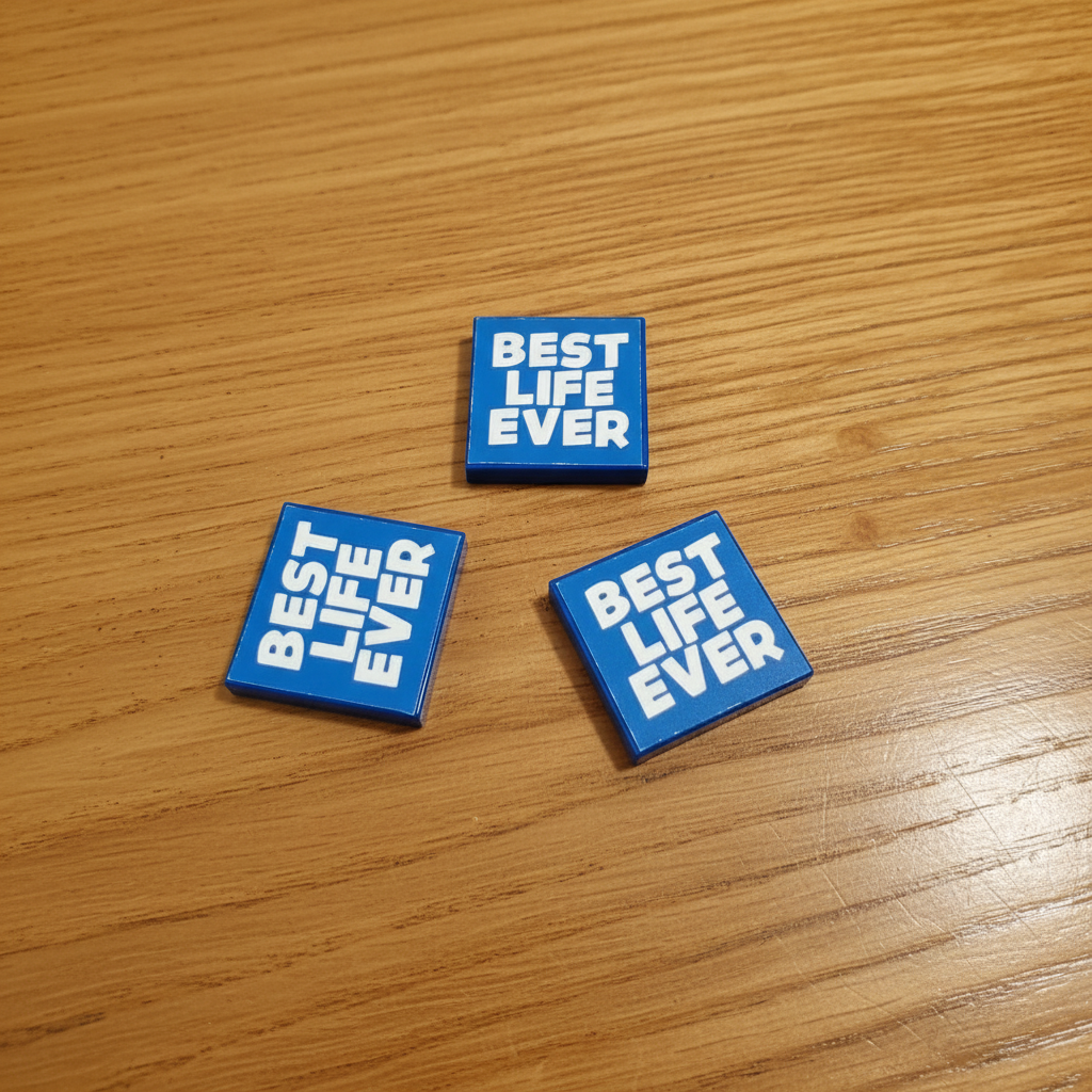 Three blue square brick tiles with 'BEST LIFE EVER' text on a wooden surface