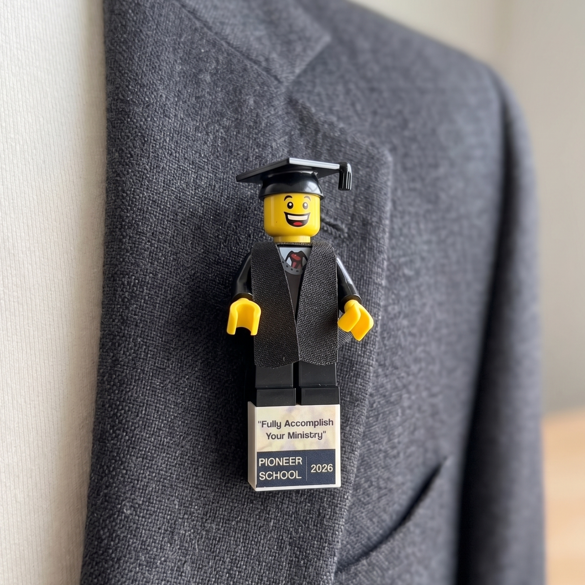 Pioneer School graduate brick figure lapel pin with a diploma tile