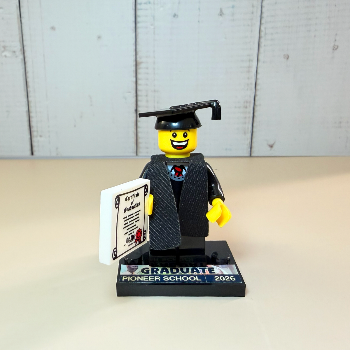 Pioneer School graduate brick figure in a graduation cap on a decal baseplate