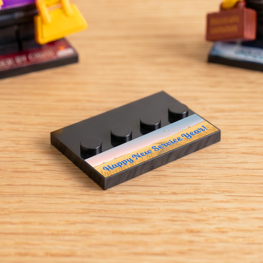 Black brick figure display stand with a 'Happy New Service Year!' decal